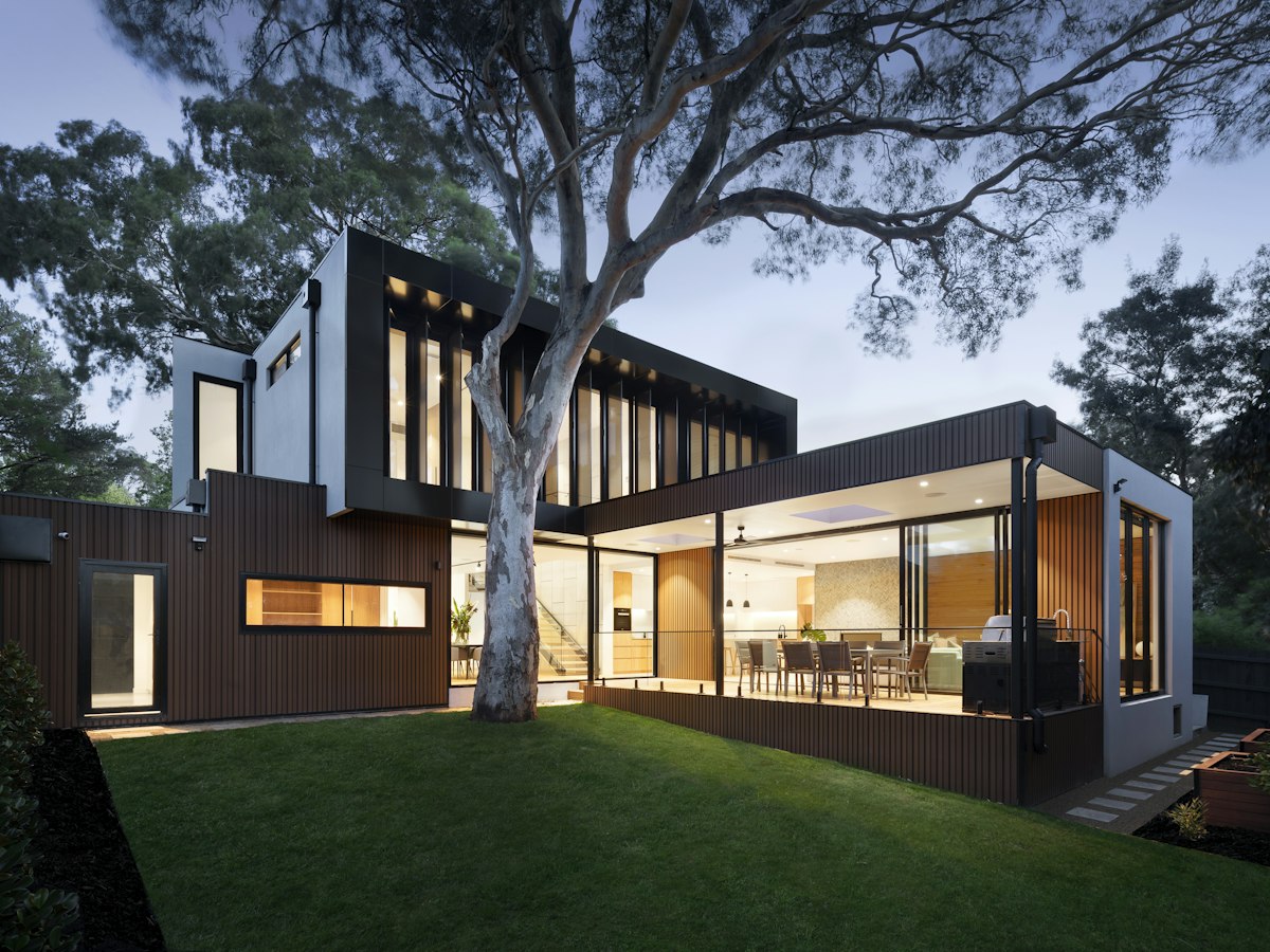 Modern two-story home exterior with mixed siding and large windows at dusk