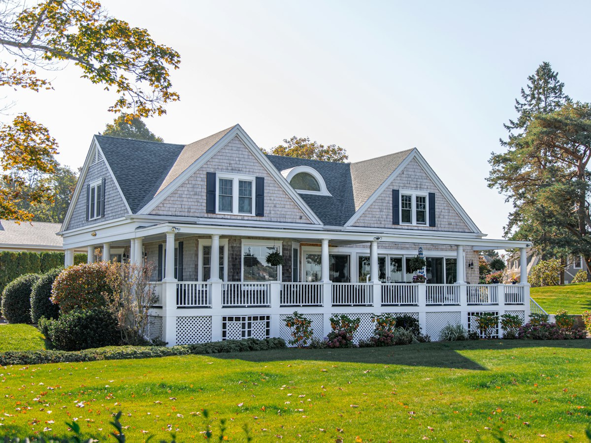 Shingle-style home with cedar shake siding and white wraparound porch